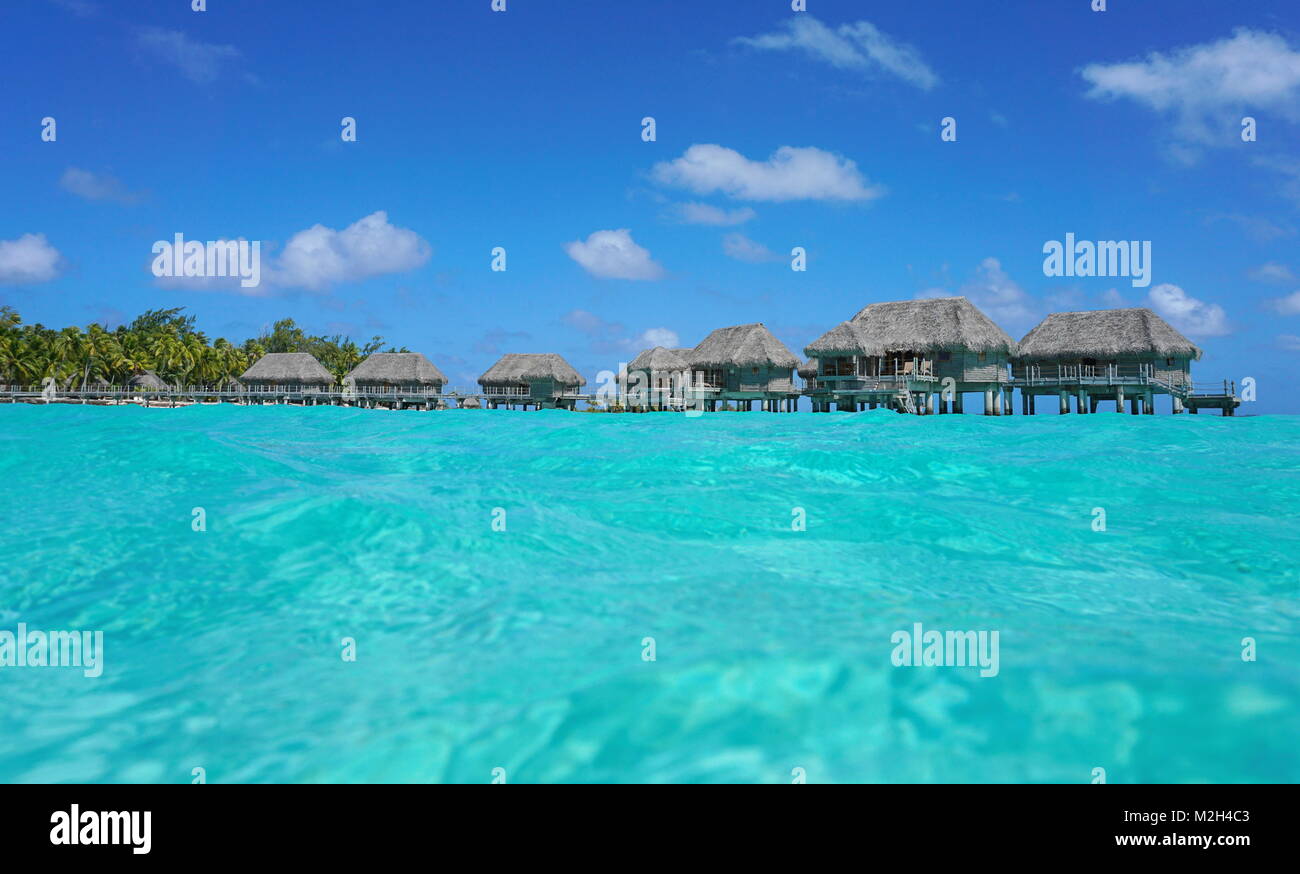Bungalows sur pilotis au toit de chaume dans un lagon tropical, vu à partir de la surface de la mer, l'atoll de Tikehau, Tuamotu, Polynésie Française, océan Pacifique, Océanie Banque D'Images