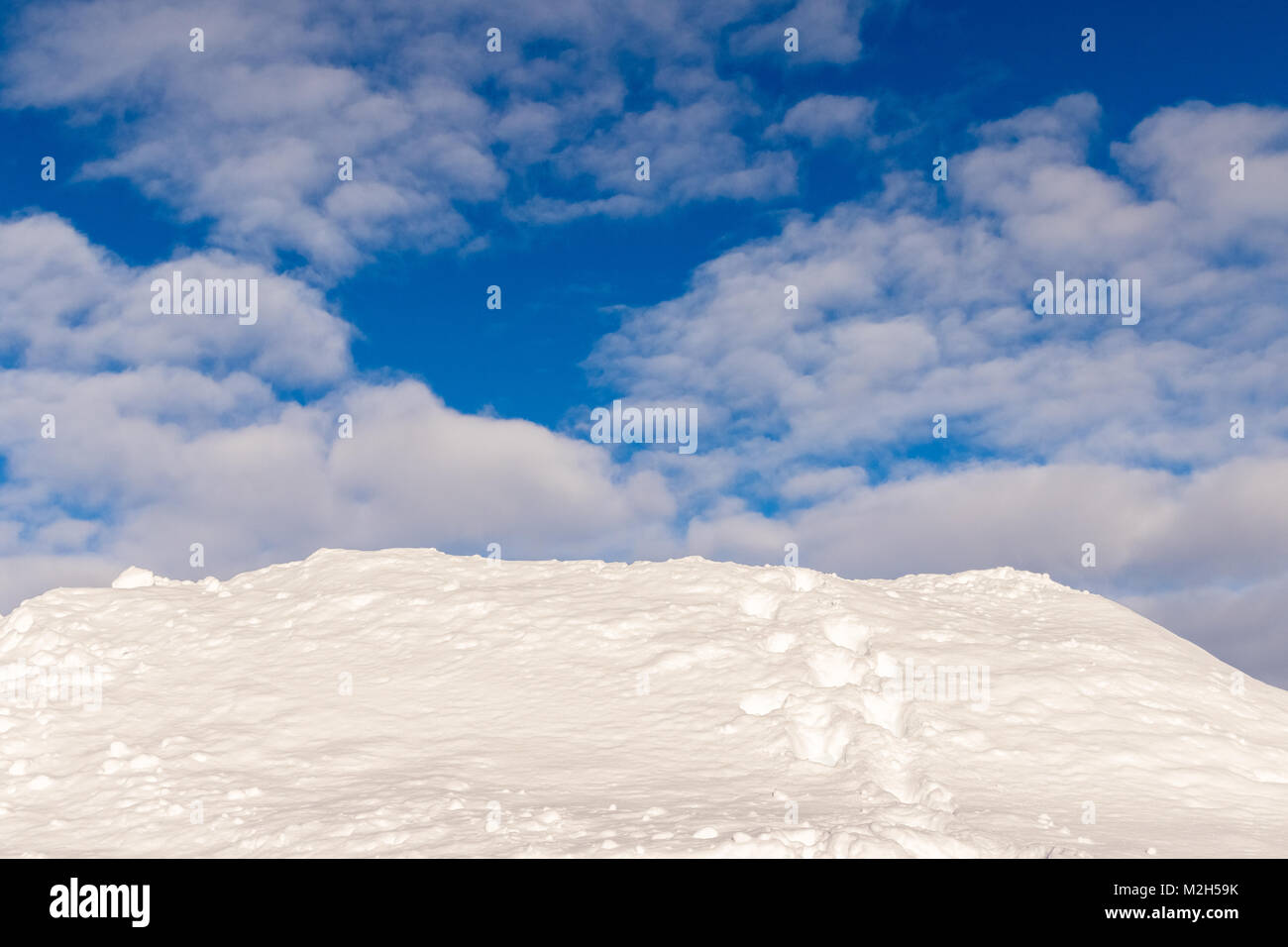 Belle image de fond de Snowdrift, une colline de neige avec les voies d'un humain, de disparaître dans le vide. Ciel bleu et les nuages blancs au-dessus. Banque D'Images