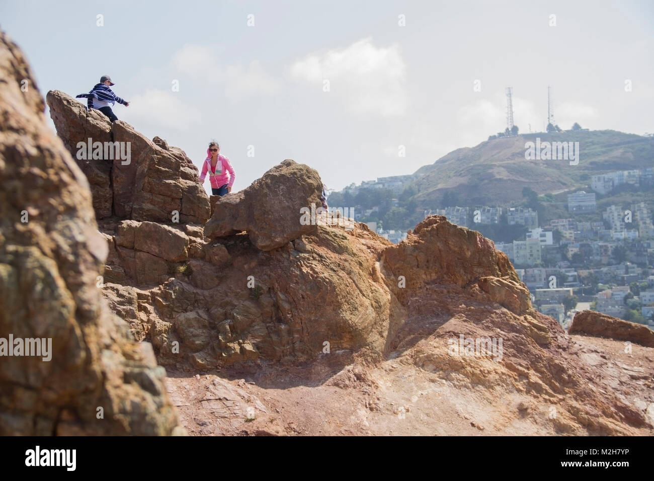 Une femme et enfant grimper sur les rochers à l'extérieur sur une chaude journée de soleil de San Francisco, en Californie. Banque D'Images