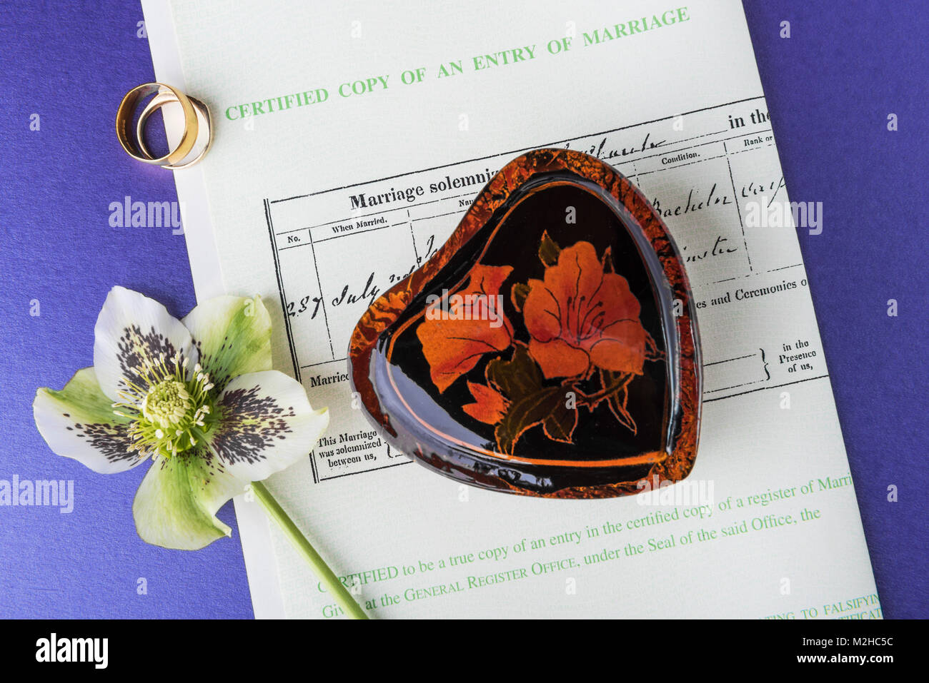 Boîte en forme de coeur et anneaux de mariage layé sur un certificat de mariage.l'amour et le romantisme de jour de mariage. Banque D'Images