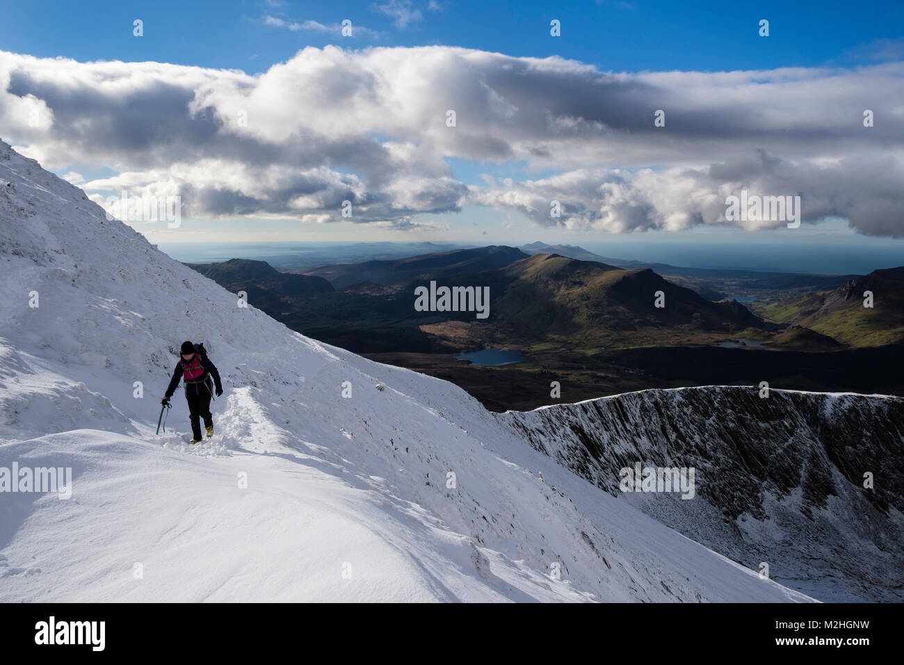 Female hiker randonnées sur chemin à Rhyd Ddu Bwlch sur Snowdon principal avec de la neige profonde en hiver dans le parc national de Snowdonia. Gwynedd, au nord du Pays de Galles, Royaume-Uni, Angleterre Banque D'Images