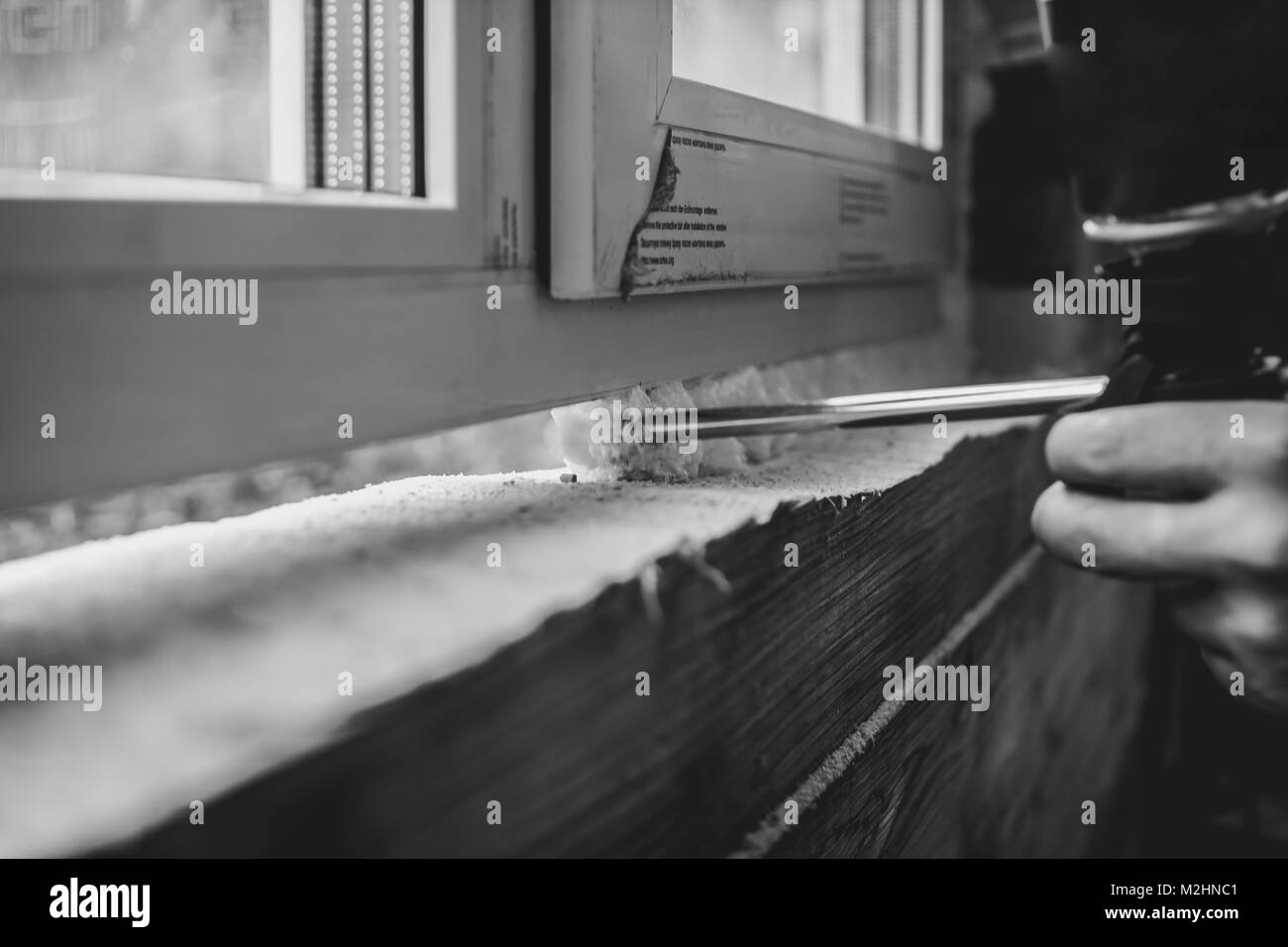 L'application de la mousse de polyuréthane. Vue détaillée des processus d'installation d'une fenêtre de polyvinyle. Travaillant pour une entreprise de construction. Banque D'Images