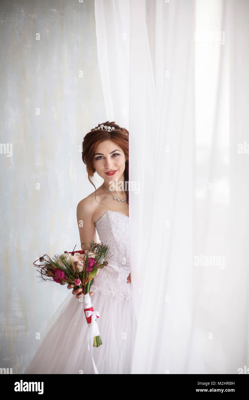 Heureux jeune mariée avec mariage bouquet mariée près de fenêtre, photo verticale Banque D'Images Heureux jeune mariée avec mariage bouquet mariée près de fenêtre, photo verticale Banque D'Images