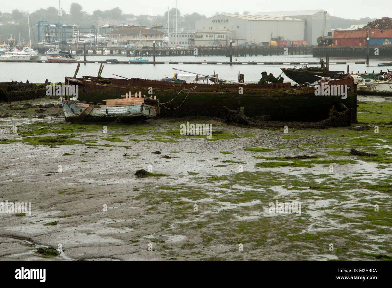 Itchen River, Southampton, à marée basse. Prises de la Northam Pont. Deux vieux bateaux délabrés au premier plan et un parc à ferrailles dans l'arrière-plan Banque D'Images