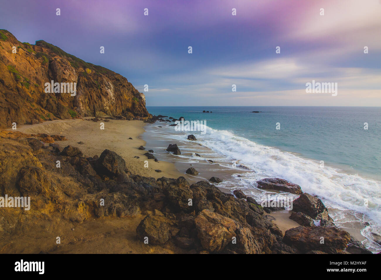 La crique isolée plage au coucher du soleil avec un ciel coloré et de l'océan l'eau qui coule autour de rock formations, Point Dume, Malibu, Californie Banque D'Images