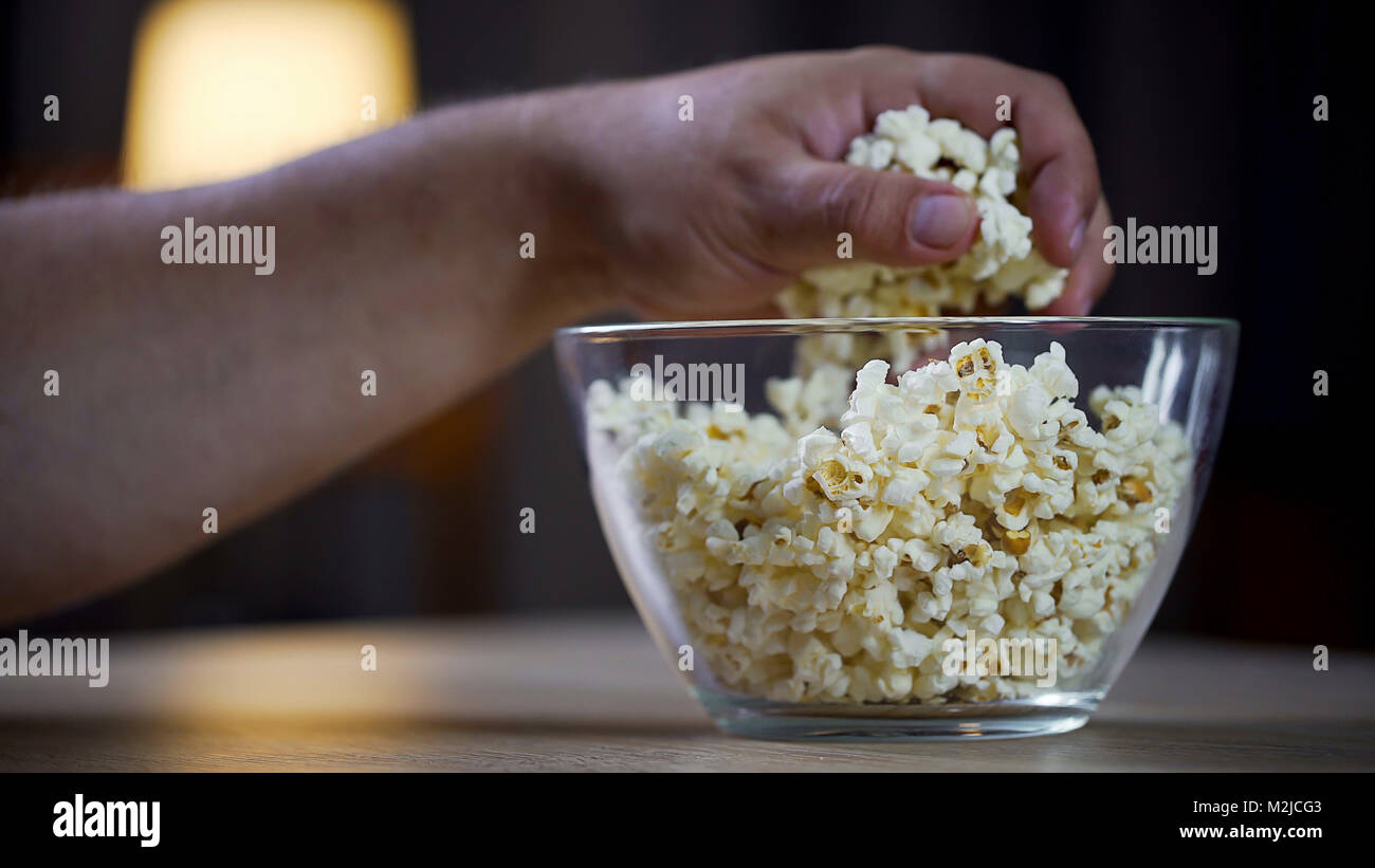 Des hommes prenant la main libre de popcorn bol sur la table, l'alimentation malsaine, addict archives Banque D'Images