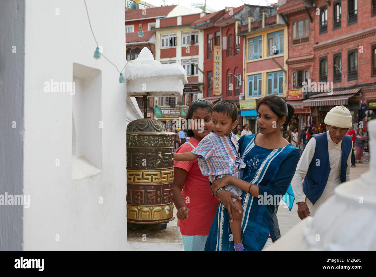 Mère avec la fille et le fils. Fils de faire tourner la roue de prière pour la bonne chance. Au plus grand stupa à Katmandou au Népal Banque D'Images