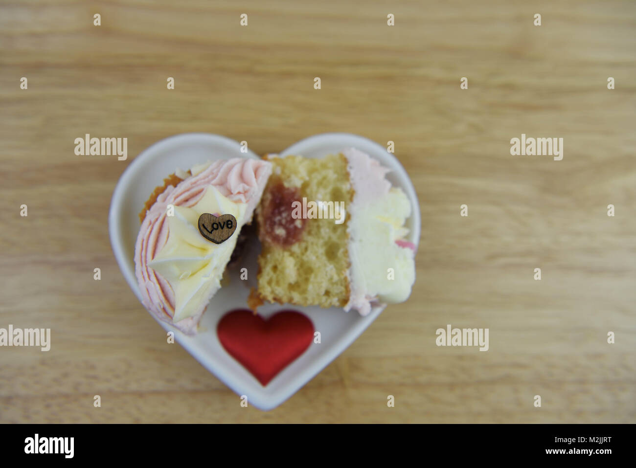 L'alimentation d'un romantique saveur fraise cupcake rose et blanc et de la confiture sur une assiette blanche avec amour coeur forme décorations et le mot amour Banque D'Images