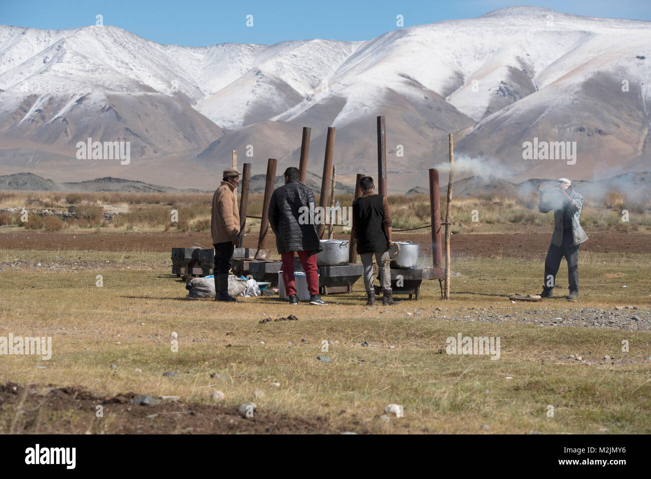 Les hommes kazakh de mouton et cuire la viande de cheval la façon traditionnelle en vue d'un jeune garçon qui le fête. Banque D'Images