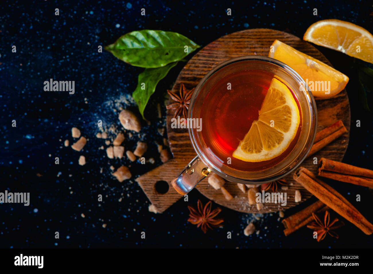 La vie encore sombre avec un verre d'eau, les tranches de citron, d'anis étoile, le sucre, les feuilles de thé et de cannelle sur un fond sombre. Tasse de thé d'automne à partir de ci-dessus. Copier l'espace. Banque D'Images