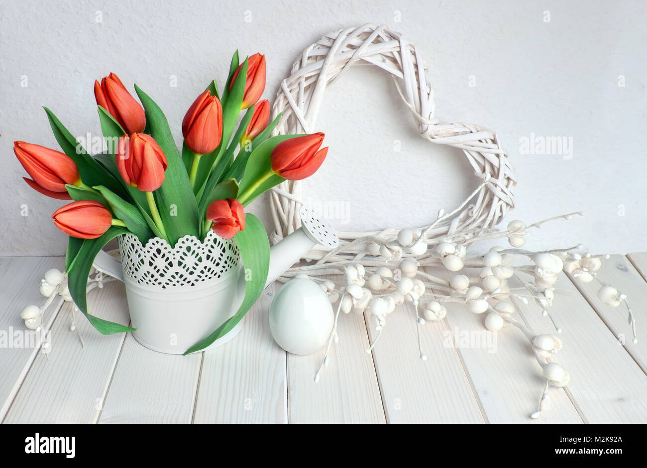 Carte de vœux de pâques avec bouquet de tulipes rouges sur fond de printemps avec des fleurs en papier, réorganisation de cœur et d'oeufs en céramique Banque D'Images