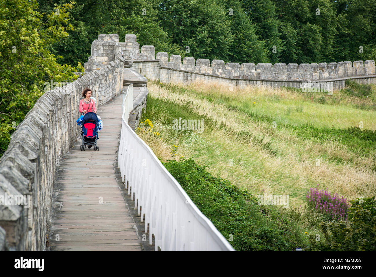 Une mère pousse la poussette vide le long des remparts historiques qui entourent la ville de York, Yorkshire, Royaume-Uni Banque D'Images