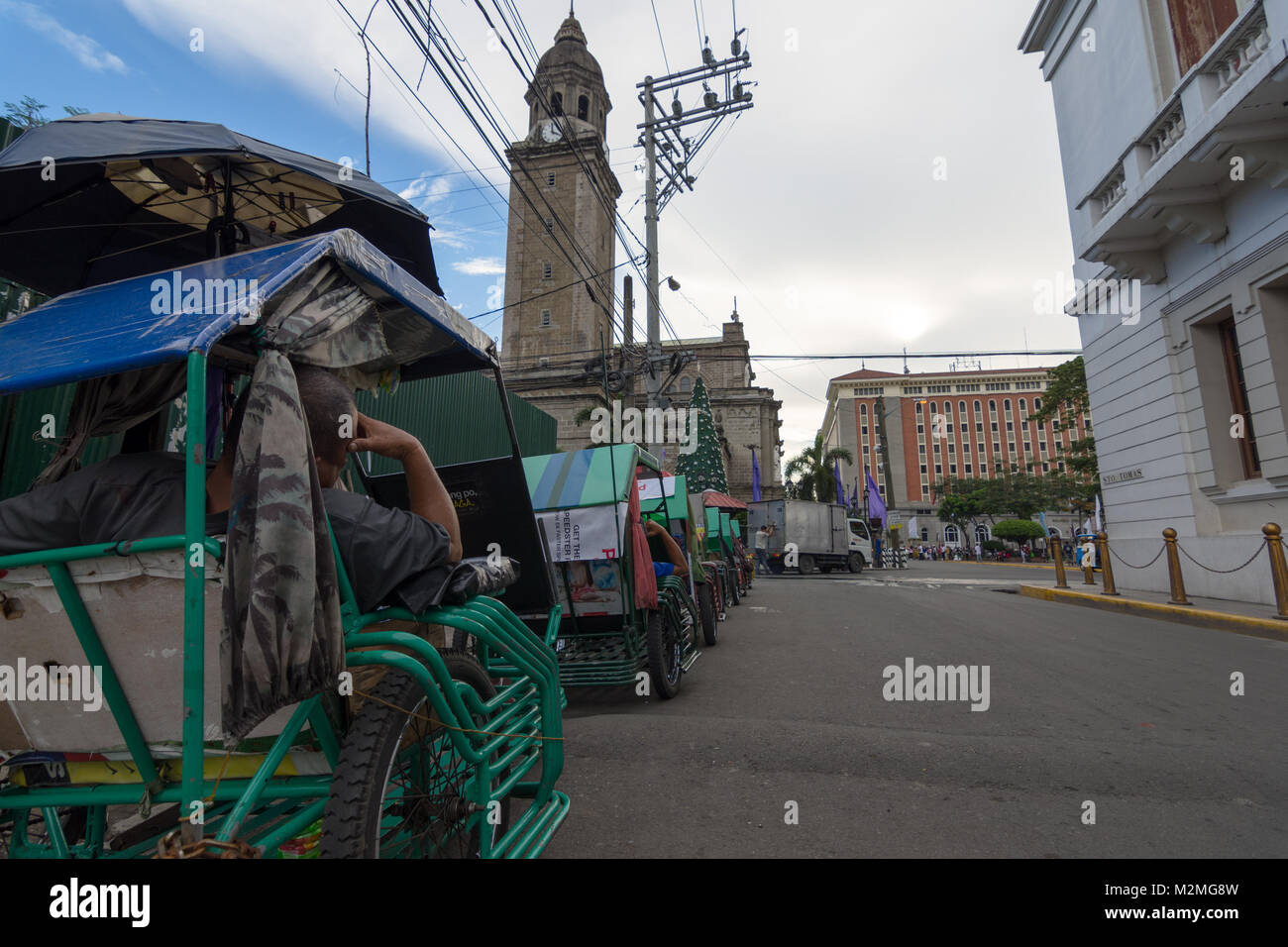 Une file d'attente de taxis pédale avec les pilotes au repos à côté de la cathédrale de Manille dans la Vieille Ville, Quartier Espagnol, Manille, Philippines, Banque D'Images