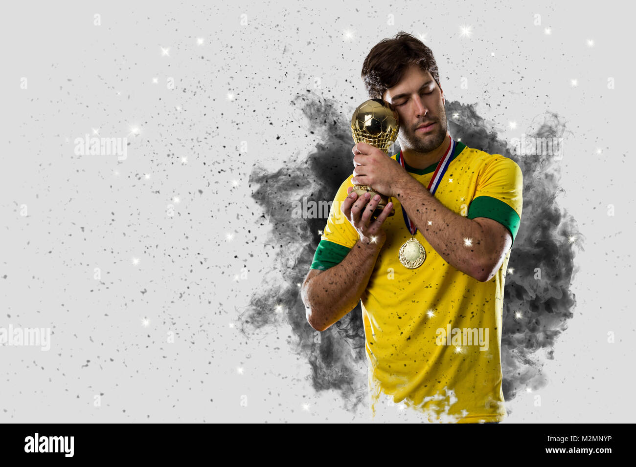 Joueur de football brésilien qui sort d'une explosion de fumée. célébrer avec un trophée à la main. Banque D'Images