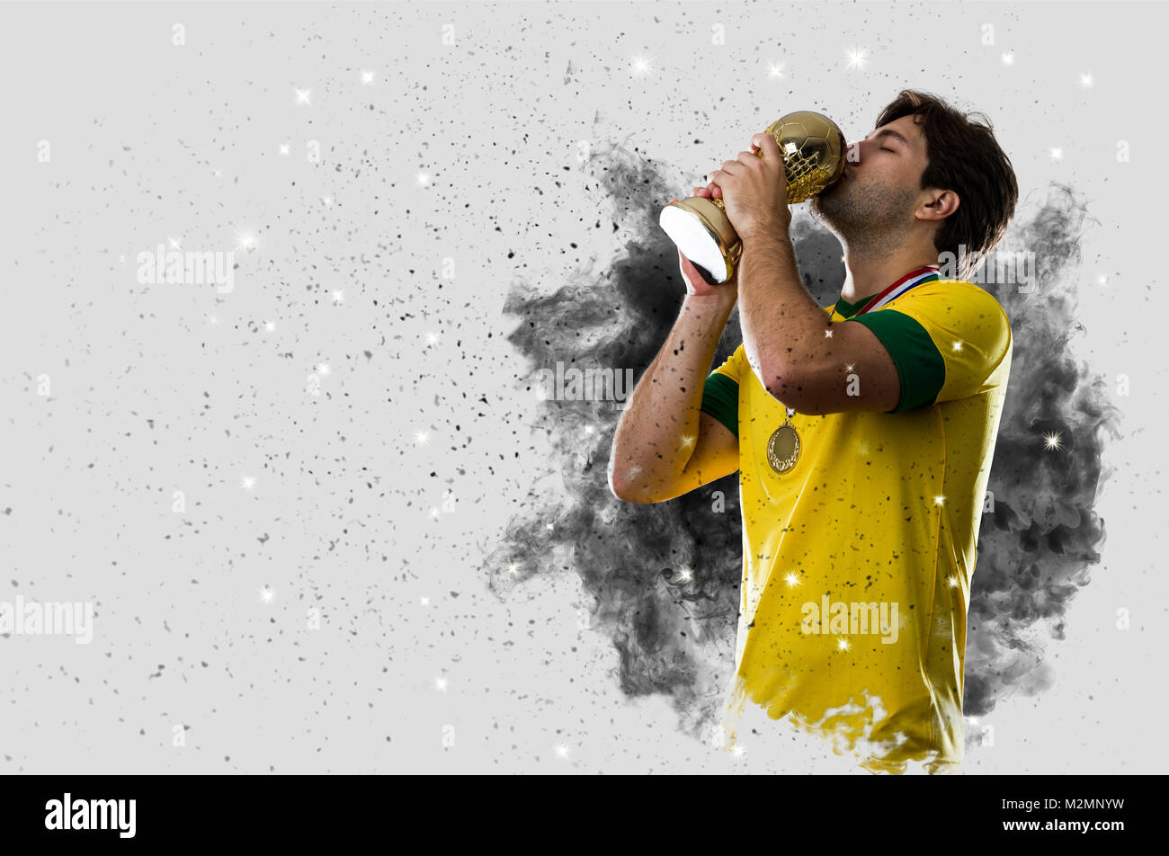 Joueur de football brésilien qui sort d'une explosion de fumée. célébrer avec un trophée à la main. Banque D'Images