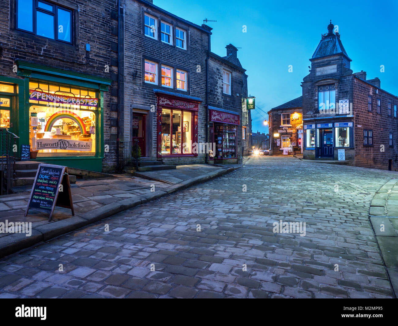 Des voyants le long de la rue principale pavée de Haworth Village à la tombée de la West Yorkshire Angleterre Banque D'Images