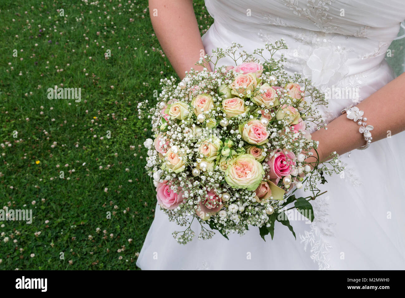 Slim blanc mariée en satin robe délicate broderie luxueuse holding en mains  fresh bright colorful mariage bouquet de roses avec de l'herbe verte sur  Photo Stock - Alamy