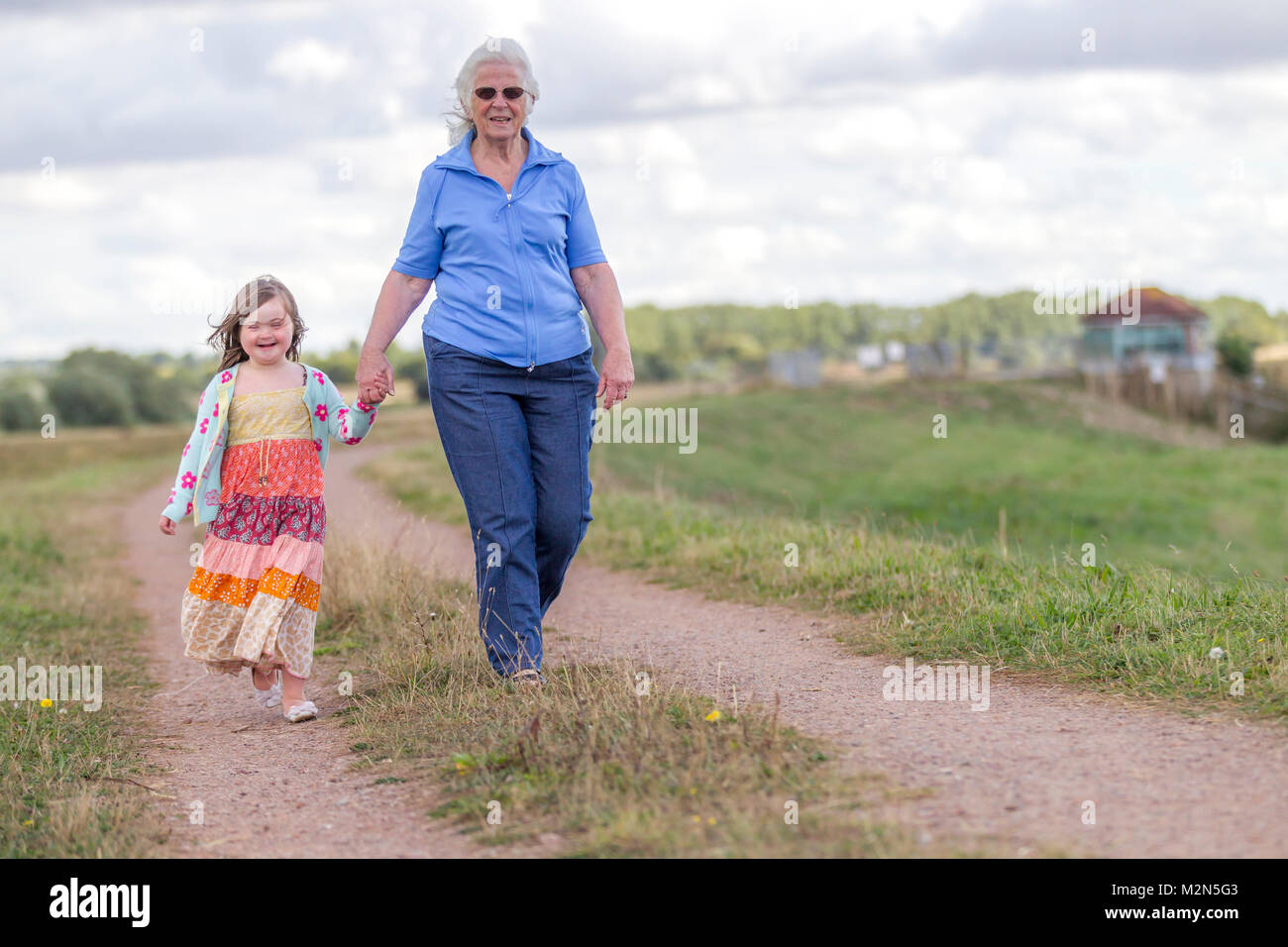 Jeune fille avec le syndrome de Down profitant de l'ensoleillement du matin avec grandparants. Banque D'Images