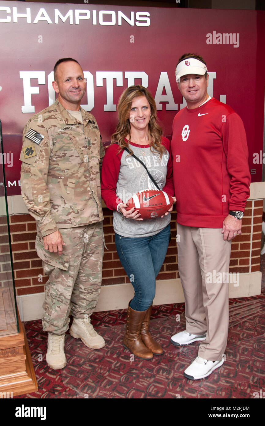 1er Sgt. Cerveau Curtis (à gauche), et la femme, Lori Curtis (centre), posent pour une photo avec l'entraîneur Bob Stoops (droite), entraîneur-chef de l'équipe de football de l'Oklahoma Sooners, suivant l'Sooners gagner contre Iowa State samedi. Brian Curtis est rentré chez lui au début de son récent déploiement en Afghanistan et suprirsed sa famille pendant le match de football. L'Université d'Oklahoma a déclaré le samedi comme jour d'appréciation militaire et fourni gratuitement des billets de 200 soldats et aviateurs, Oklahoma. PHOTO : SGT. Daniel Nelson Jr., 145e MPAD, Texas Army National Guard ou Journée de reconnaissance militaire 2013 004 par Oklaho Banque D'Images