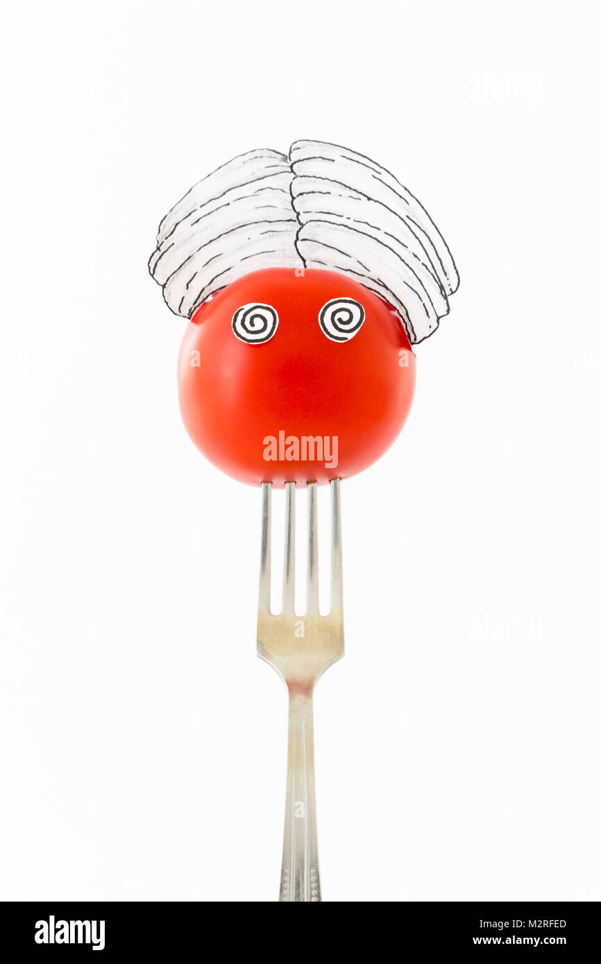 Tomate rouge sur fond blanc avec turban assis comme un fakir sur une fourchette d'argent représentant indien. Banque D'Images