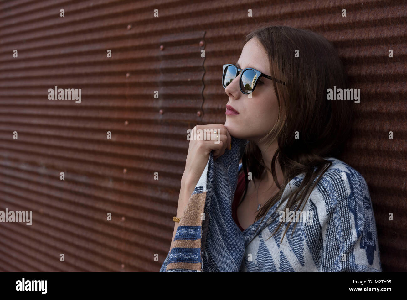 Jeune femme s'appuie contre la tôle mur à l'extérieur, portrait Banque D'Images