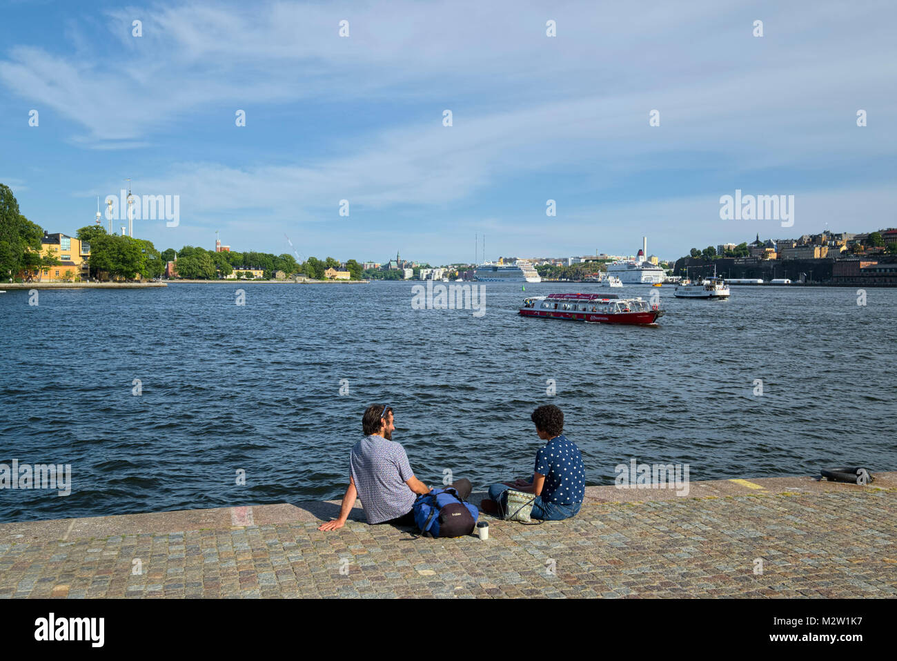 La Suède, Stockholm, jeune couple sur la rive en face de la circulation maritime Banque D'Images