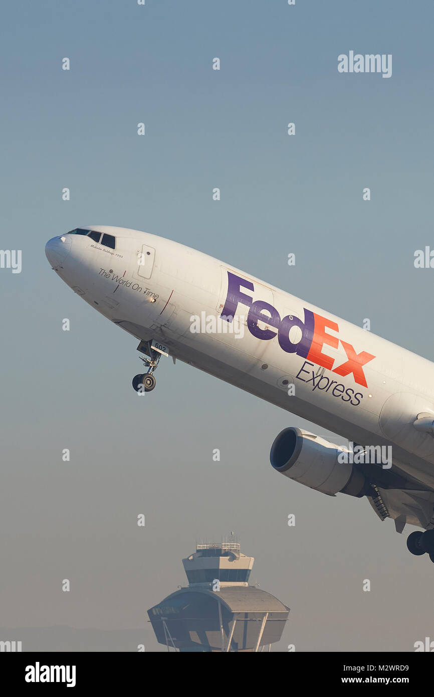FedEx Express MD-11 Cargo Jet Avion au décollage de l'Aéroport International de Los Angeles, la tour de contrôle en arrière-plan, en Californie, USA. Banque D'Images