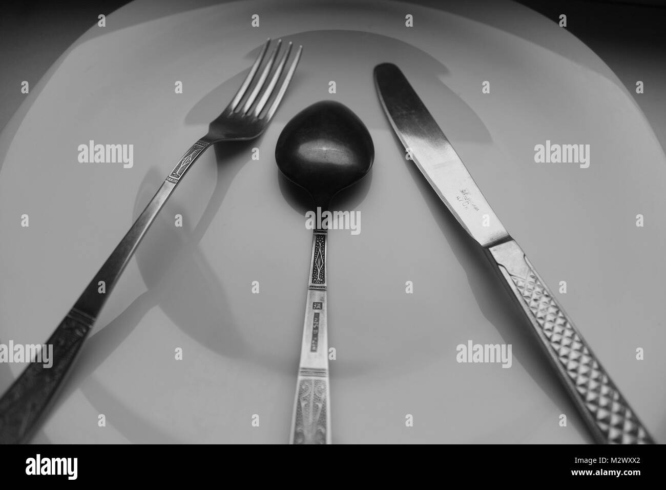 Grande Assiette de porcelaine blanche vide avec couteau, fourchette et cuillère pour préparer le tableau de service pour le dîner Banque D'Images
