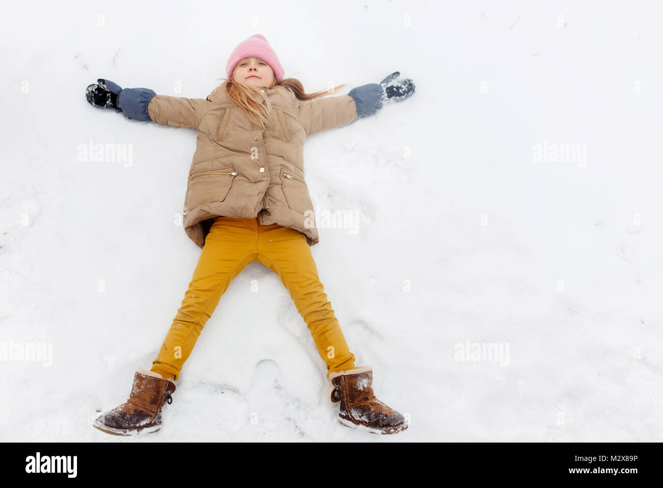 Photo de jeune fille allongée sur le dos dans la neige au parc Banque D'Images