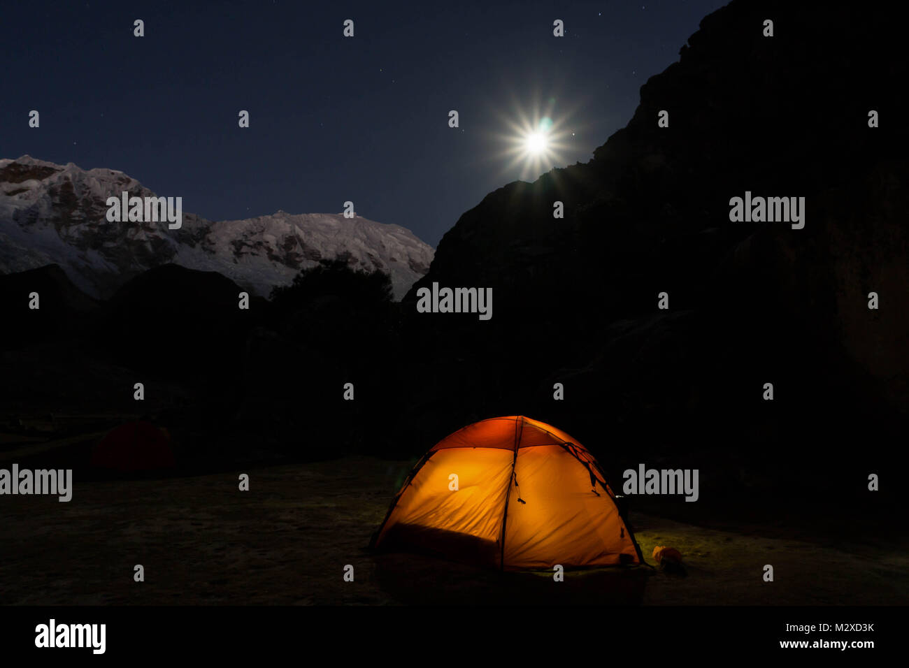 Sous une pleine lune dans un paysage de montagnes avec une orange tente dans l'avant-plan Banque D'Images