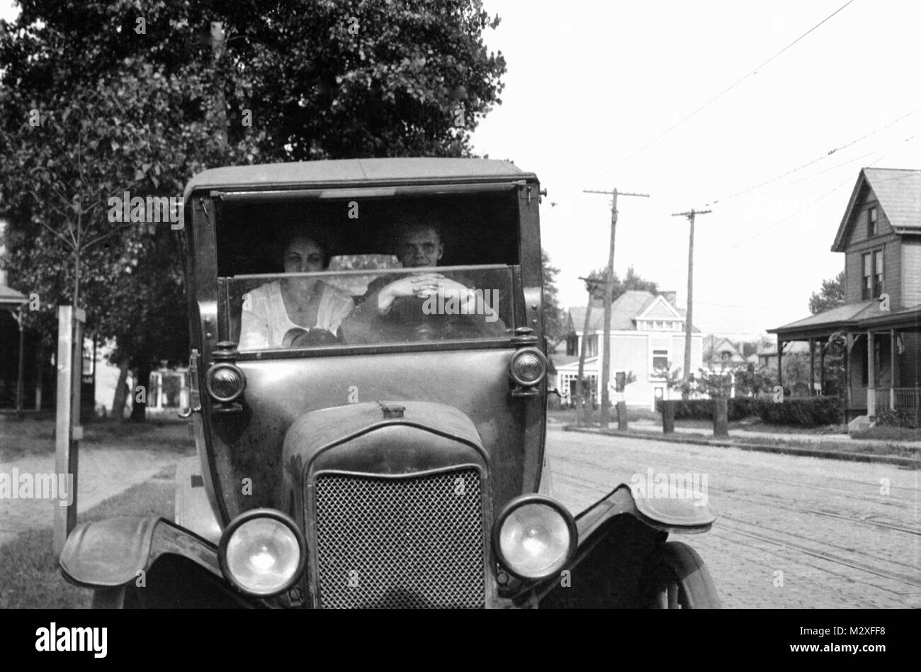 L'homme et la femme posent un grave grève derrière le volant de leur début de l'automobile, de ca. 1924. Banque D'Images
