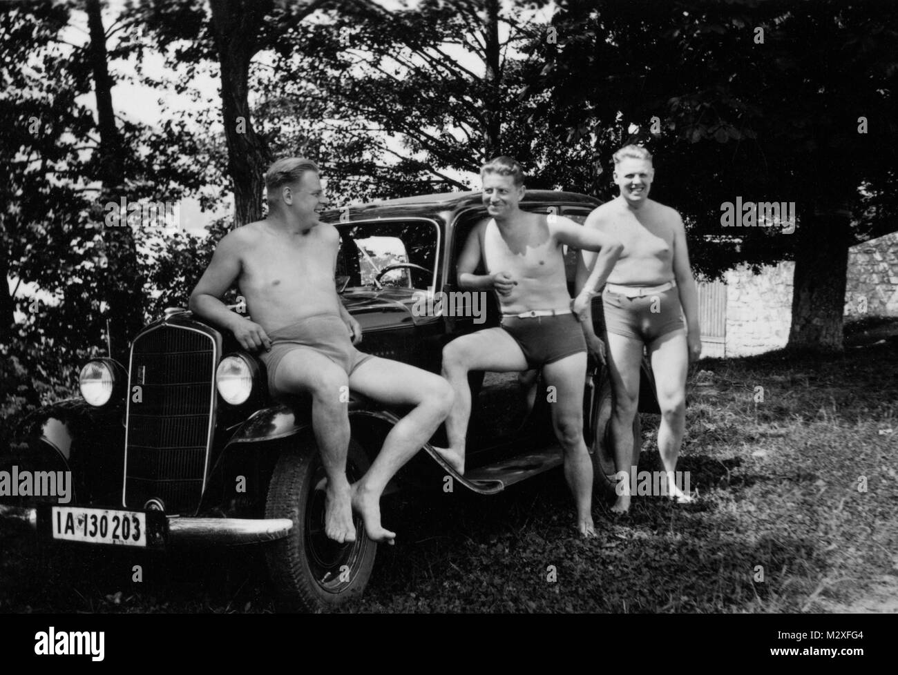 Trois gars allemand à bad maillots de traîner sur la voiture, ca. 1935. Banque D'Images