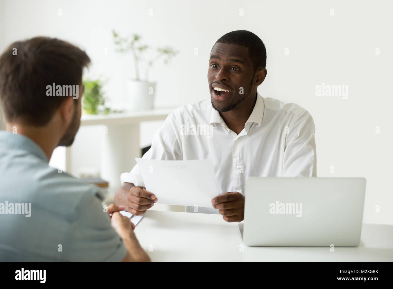 Bonne première impression au concept d'entrevue d'emploi, responsable des ressources humaines de l'Afrique de l'excité impressionné par les réalisations de carrière à reprendre des candidats de race blanche, noire em Banque D'Images