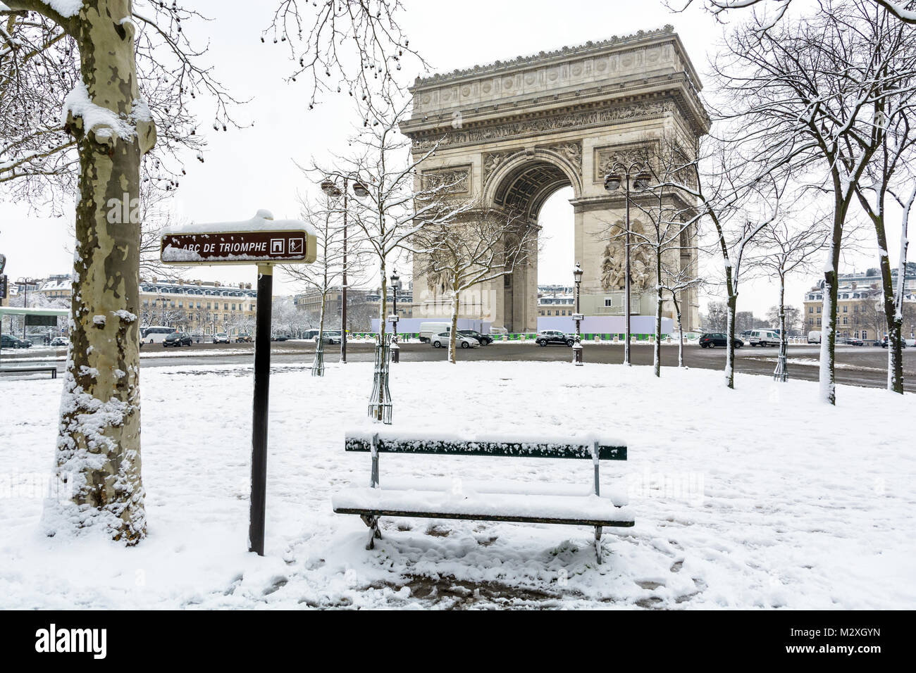L'hiver à Paris dans la neige. L'Arc de Triomphe avec un banc public couvertes de neige au premier plan. Banque D'Images