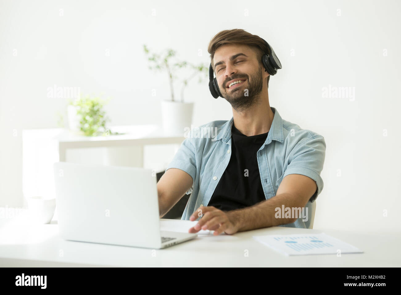 Jeune homme détendu en profitant de la musique sur ordinateur portable casque Banque D'Images