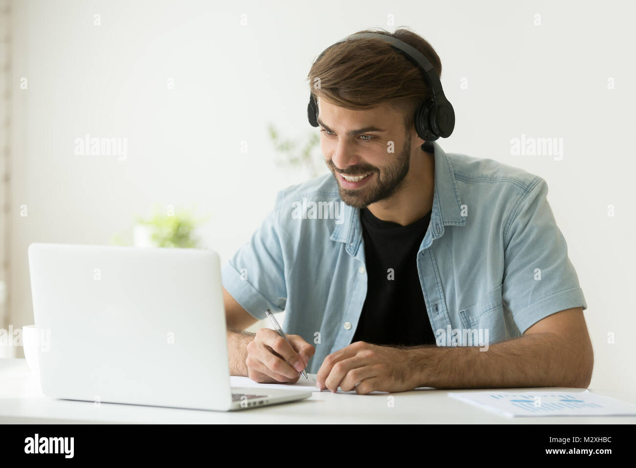 Smiling man wearing headphones à faire écran à l'ordinateur Banque D'Images