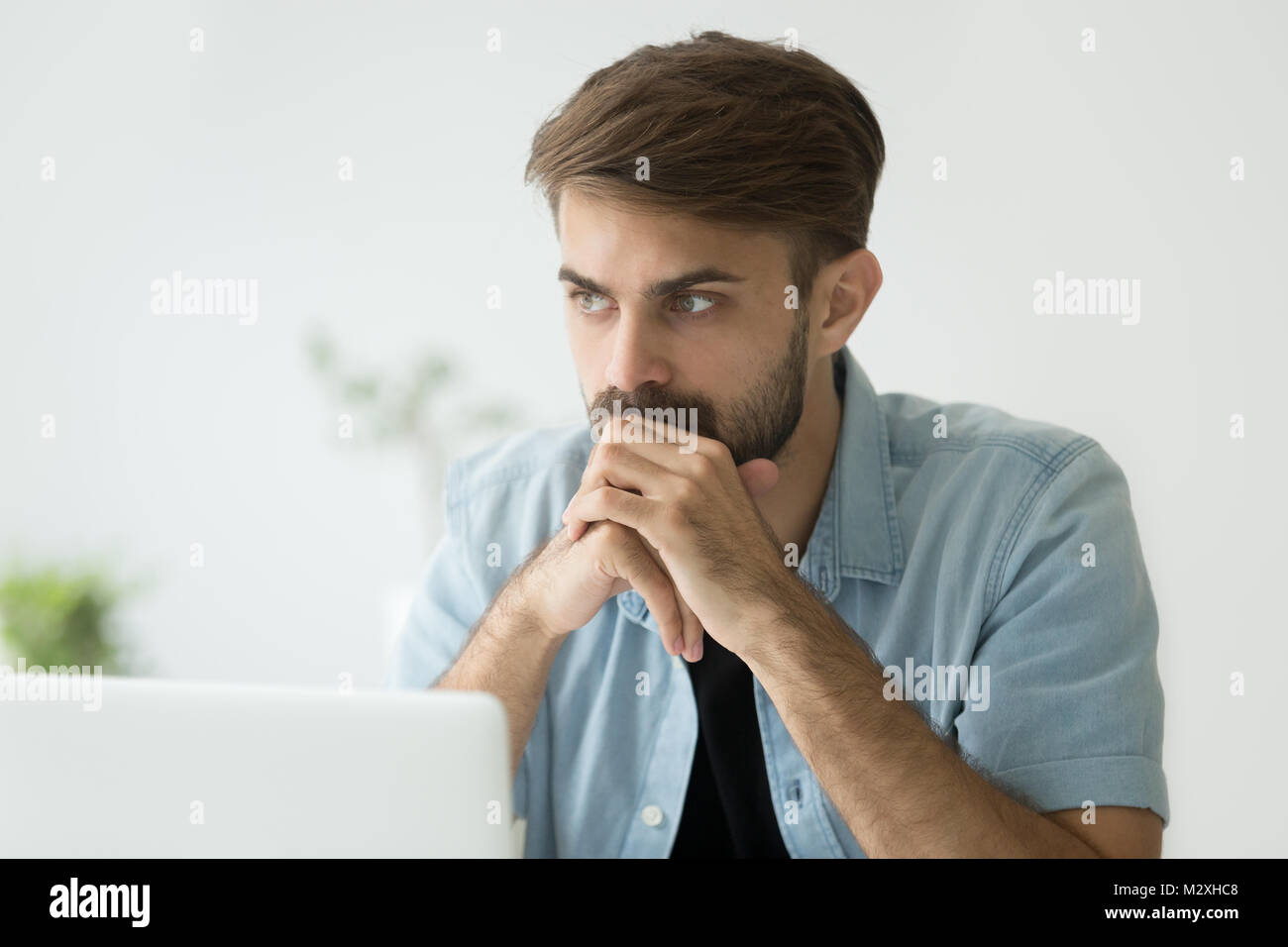 Homme sérieux attentionné perdue dans ses pensées en face de l'ordinateur portable Banque D'Images