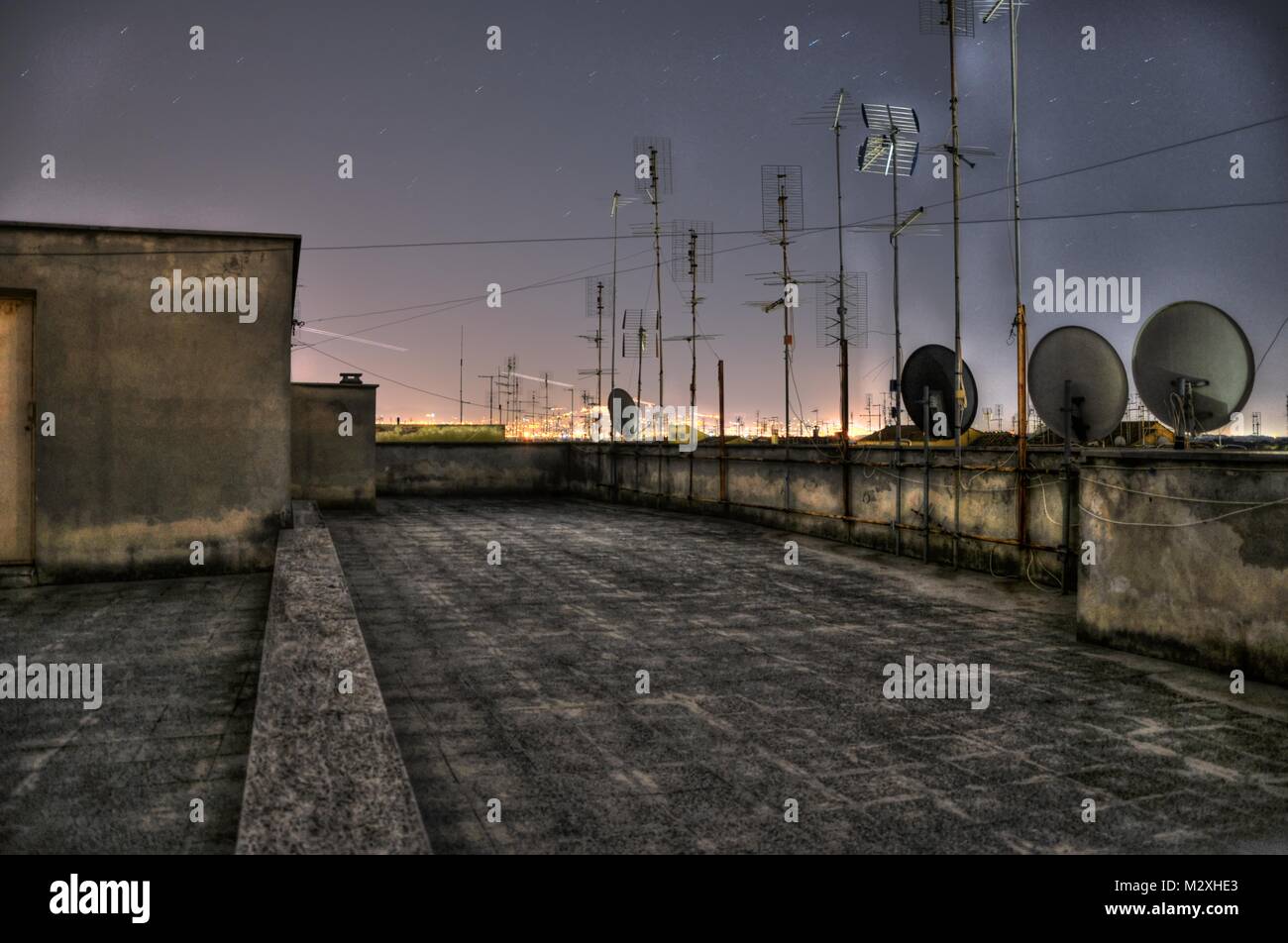 Paysage de nuit à partir de la terrasse d'un bâtiment avec les antennes de télévision et les lumières au loin Banque D'Images