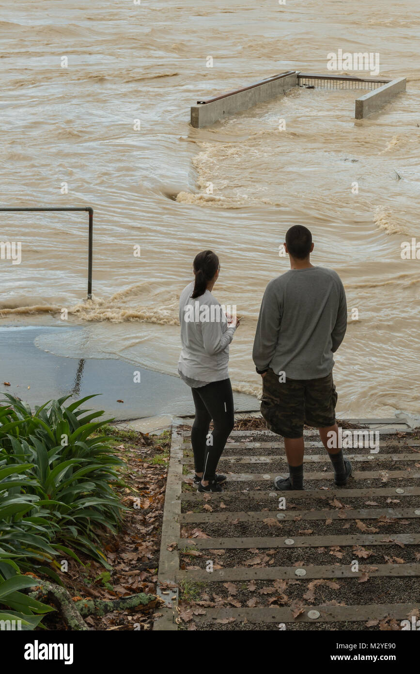 Un couple devant un Chemin submergé et poste d'observation près de l'Esplanade de Victoria que la rivière Manawatu fait rage pendant une inondation partielle de la région. Banque D'Images