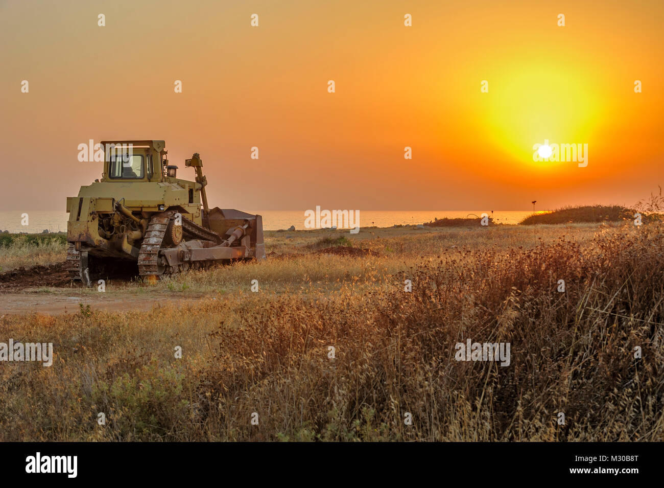 Bulldozer sur la plage au coucher du soleil Banque D'Images