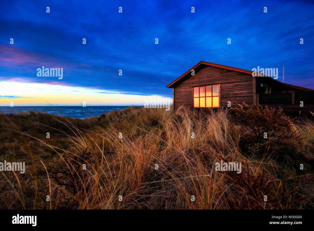 Maison dans les dunes au coucher du soleil sur une plage près de Hirtshals. Banque D'Images