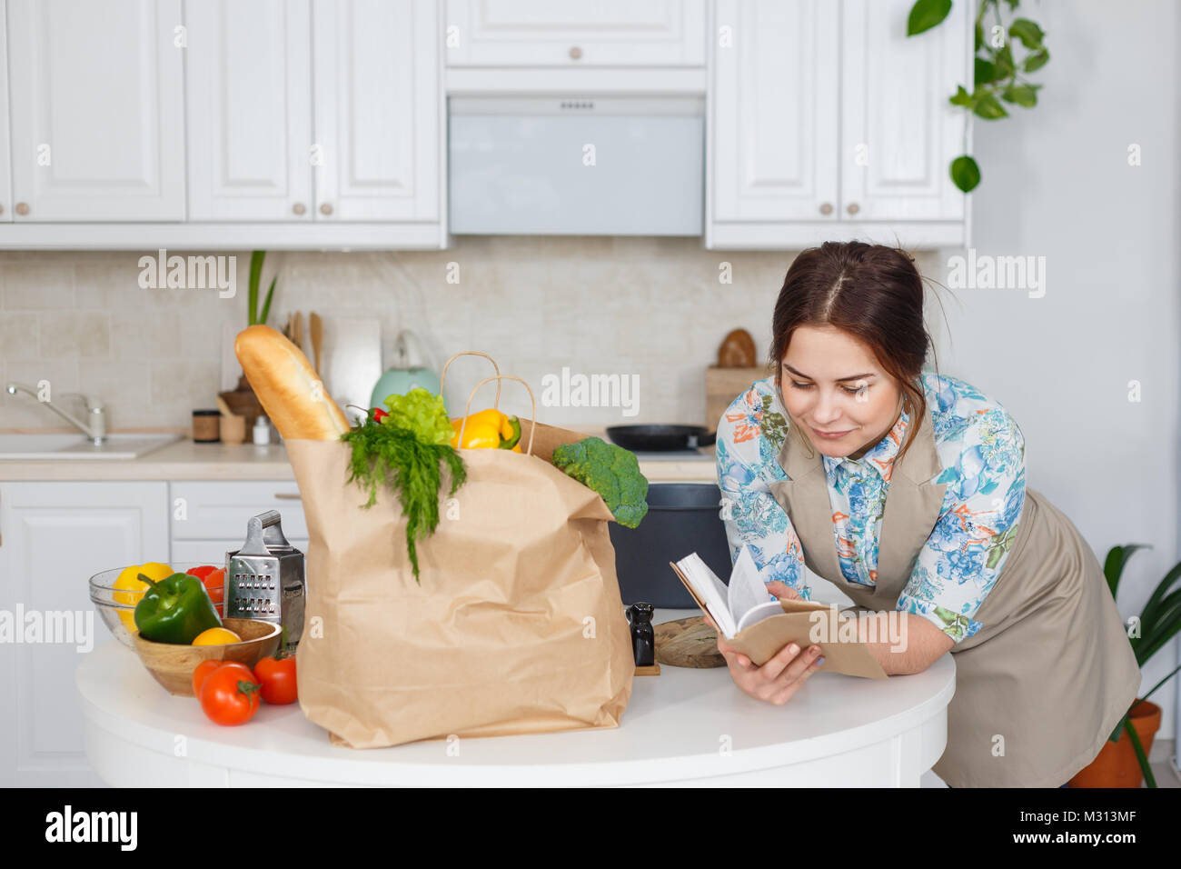Jeune femme au foyer avec recueil de recettes dans la cuisine Banque D'Images