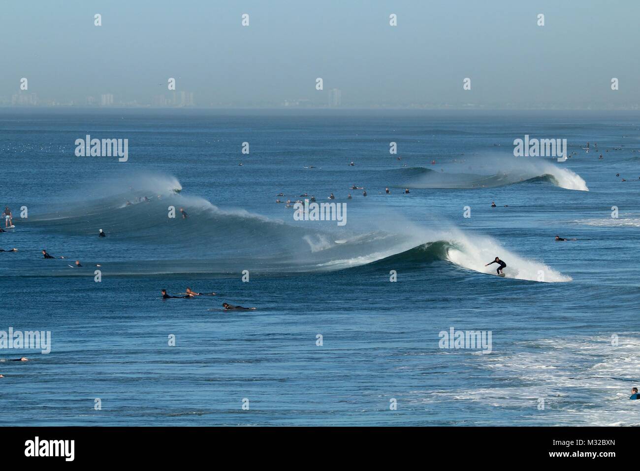Surfers surf vagues avec l'éolien offshore à Huntington Beach Californie Banque D'Images