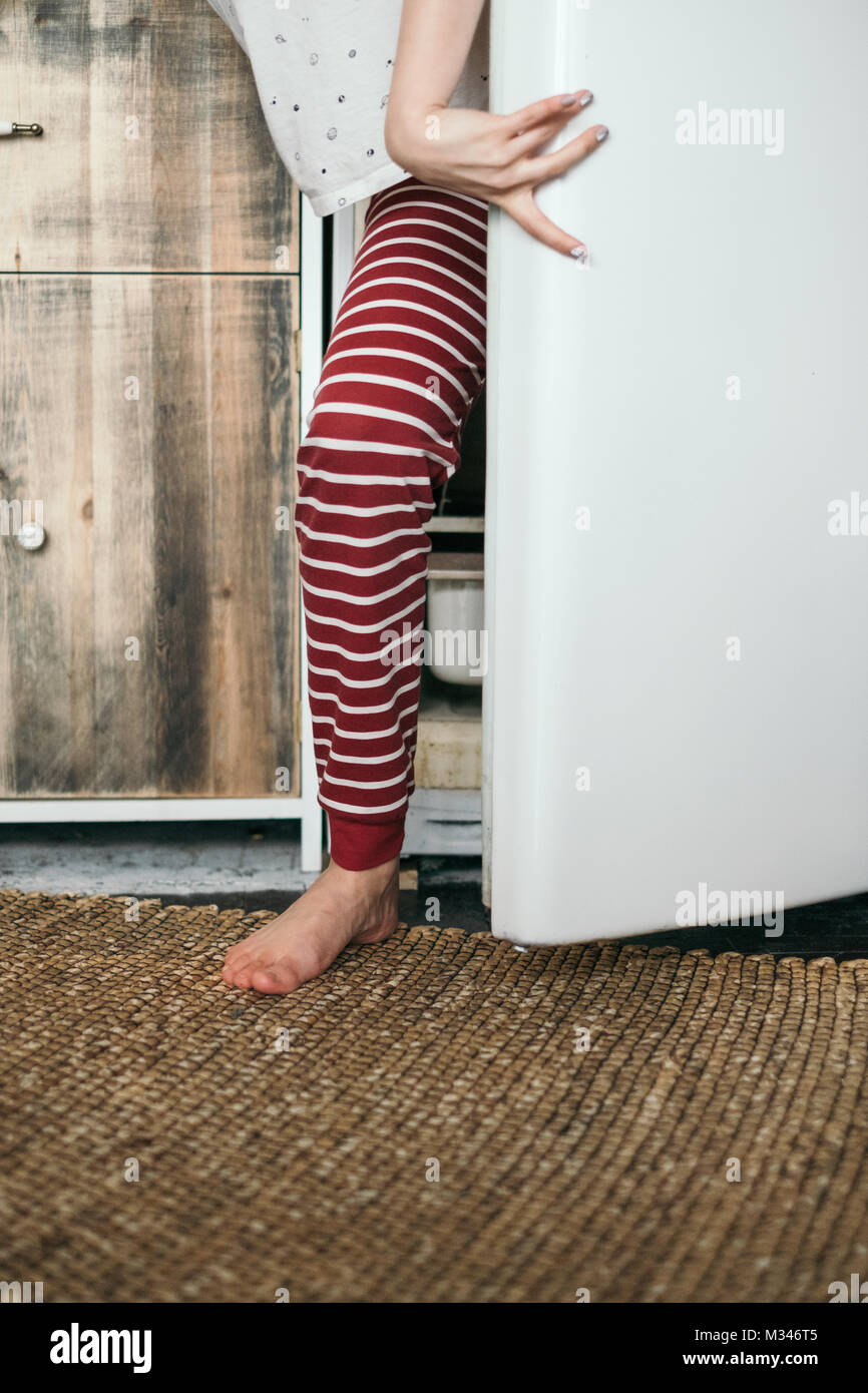 Femme debout par un frigo dans la cuisine Banque D'Images
