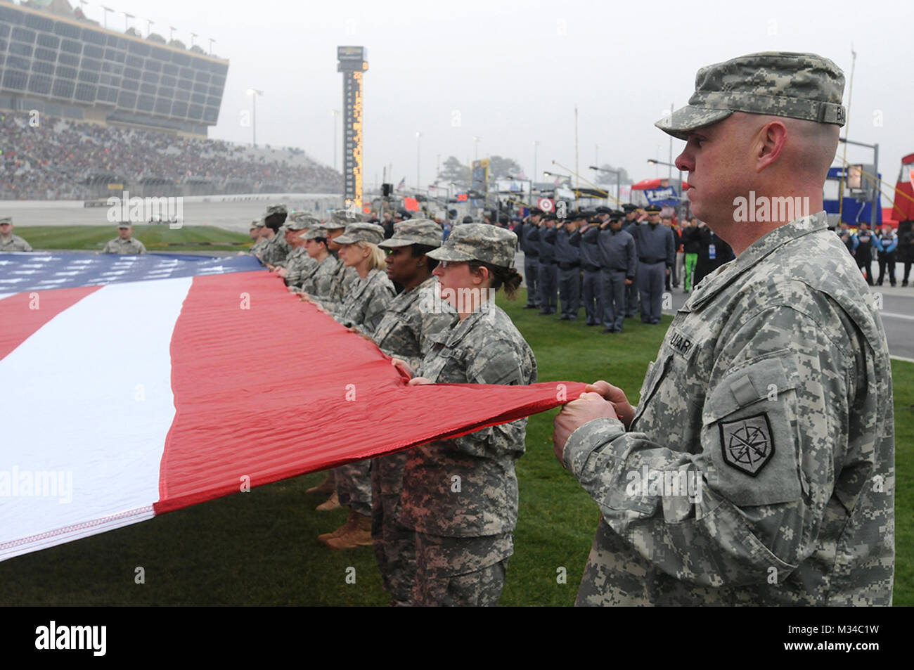 Hampton, ga., 1 mars 2015 - Des soldats de l'Armée de la Géorgie et de la Garde nationale au garde à vous comme ils tiennent un grand drapeau américain pendant l'hymne national avant le début de la de l'honneur 500 plis QuikTrip à Atlanta Motor Speedway. NASCAR - QT par la Garde nationale de Géorgie Banque D'Images