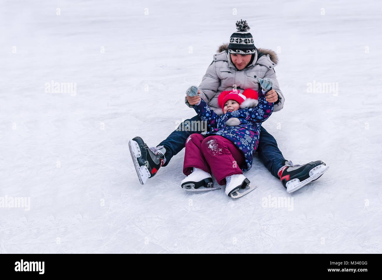 Adorable petite fille apprendre à patiner en formation. le patinage. Une  petite fille et un jeune homme est tombé sur la patinoire. Activités de  plein air hivernales. Le sport amateur Photo Stock -