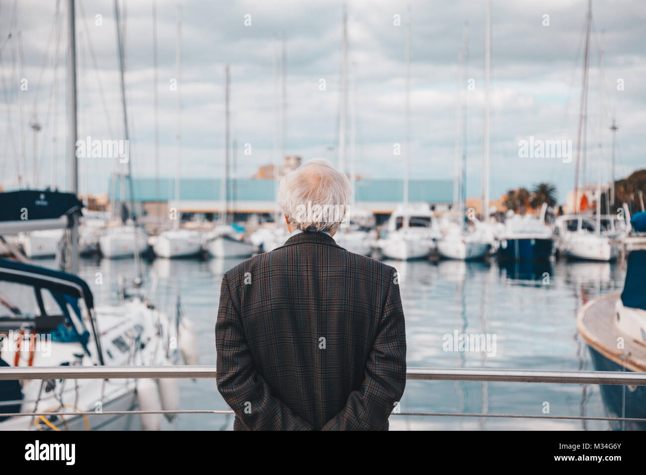 Vieil homme à poils blancs et bien habillés à l'bateaux du port Harbour - concept solitaire Méditation Banque D'Images