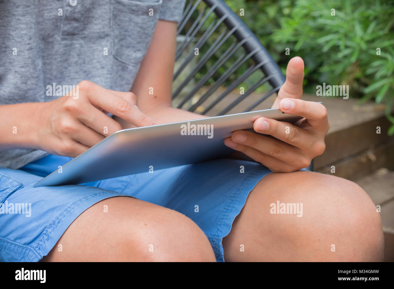 Garçon ; tablet ; piscine ; jardin ; parc ; les genoux ; loisirs ; fun ; affichage ; notes ; Internet ; lecture ; ; ; ; la technologie ; Caucase ; l'écran tactile ; attente ; ho Banque D'Images