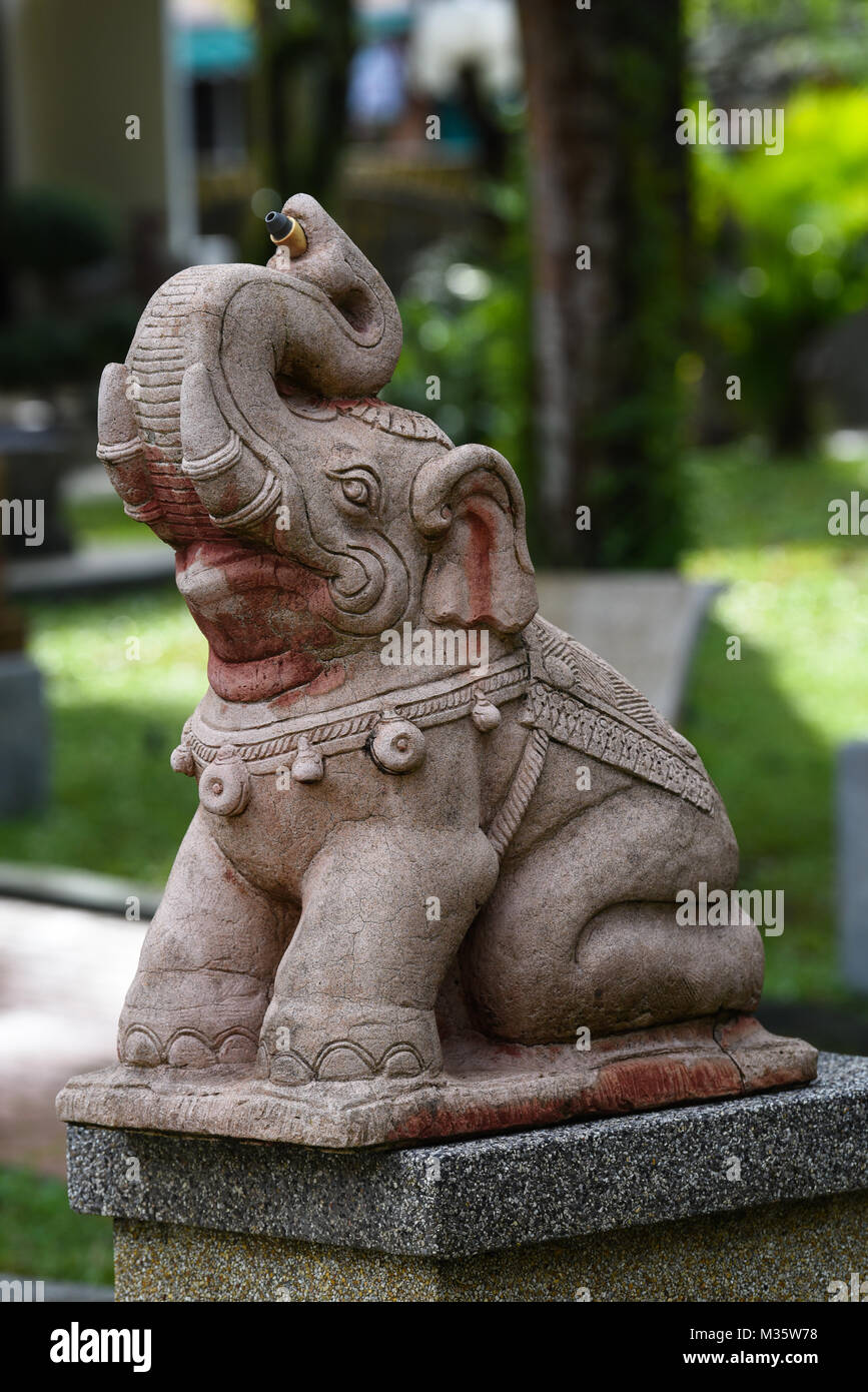Statue sculpture de pierre d'un éléphant assis avec son tronc jusqu'heureux et rire dans un jardin en Thaïlande à la lumière du jour Banque D'Images