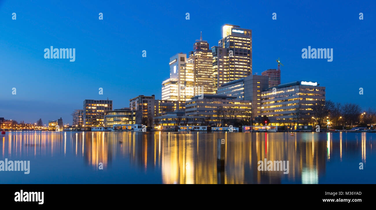 Amsterdam city skyline avec Rembrandt, Breitner et tour de Mondriaan, près de la rivière Amstel au coucher du soleil pendant l'heure bleue avec des reflets dans l'eau. Banque D'Images